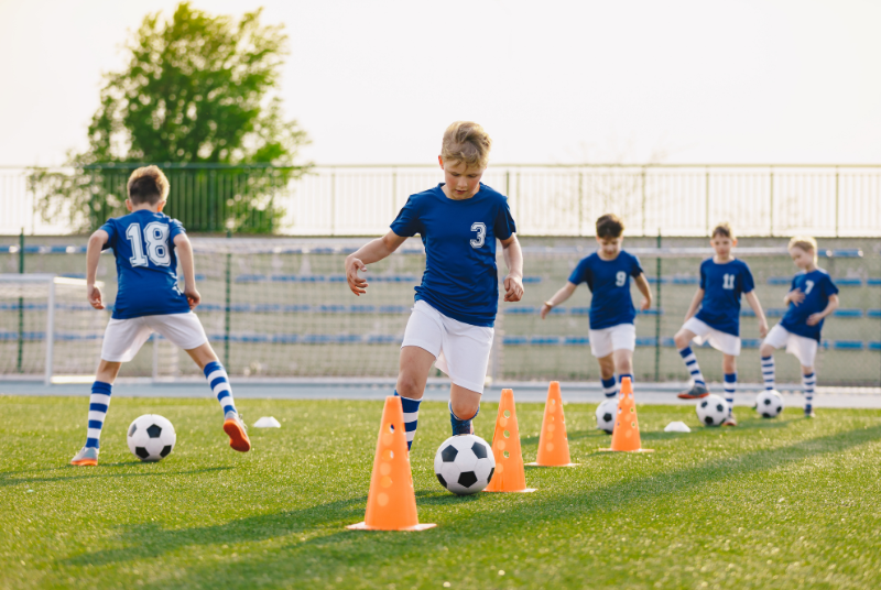 Niños jugando al fútbol en un campo con césped artificial